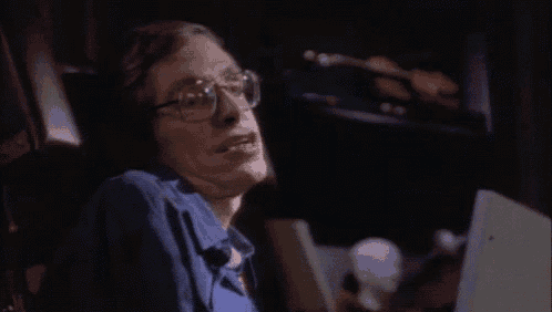 a man wearing glasses is sitting in a chair laughing .
