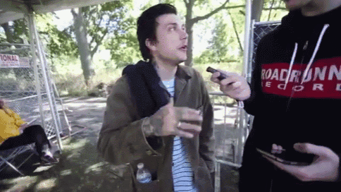 a man wearing a hoodie that says roadrunner records is talking to another man