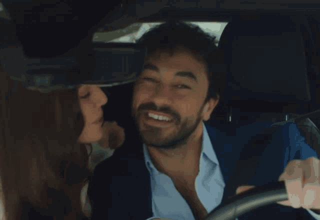 a woman kisses a man on the cheek while he smiles
