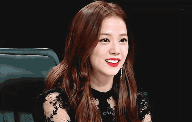 a woman in a black lace top is smiling and clapping