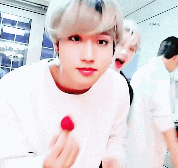 a man in a white shirt is eating a strawberry in a kitchen