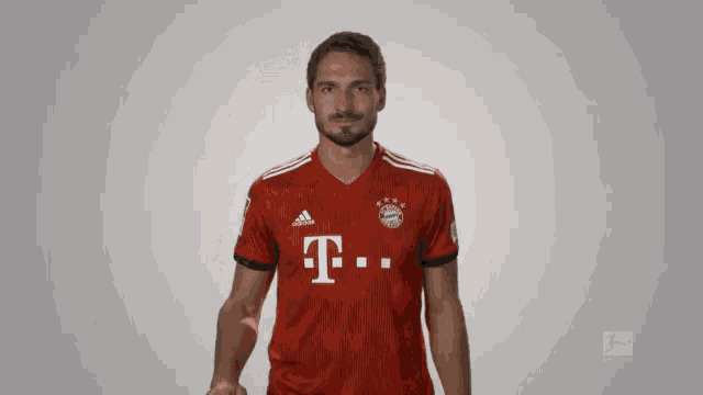 a man wearing a red adidas shirt with the letter t on the front