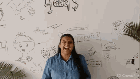 a woman is standing in front of a white board with drawings on it and a sign that says wanted