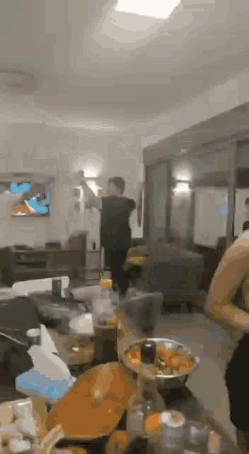 a man in a black shirt is standing in a living room with a bowl of food on a table