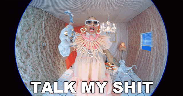 a woman in a pink dress is standing in a room with the words talk my shit below her