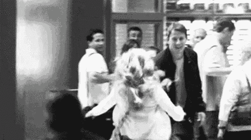 a black and white photo of a group of people walking in a crowded area .