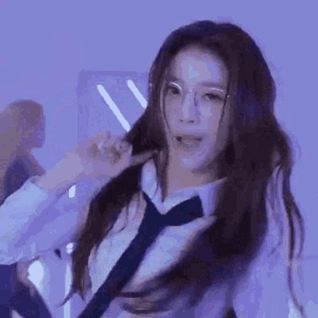 a woman wearing glasses and a tie is dancing in a room .