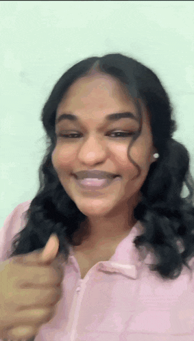 a woman is smiling and giving a thumbs up sign