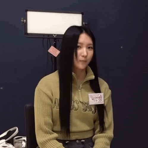 a woman with long black hair is wearing a sweater that says alesssi
