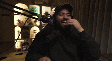 a man wearing headphones is sitting in a chair laughing