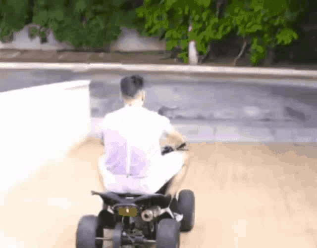 a man in a white shirt is riding a four wheeler on a wooden deck .