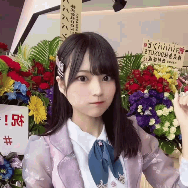 a girl stands in front of a bunch of flowers and a sign that says ' tju00 '