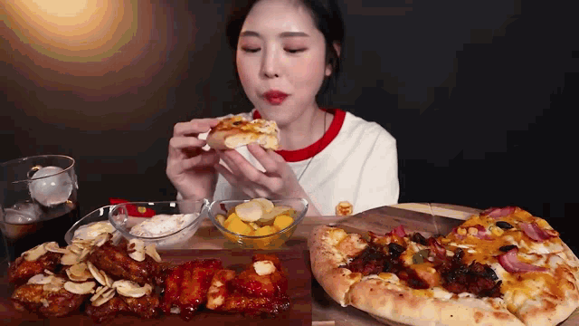 a woman is eating a slice of pizza while sitting at a table with other food .