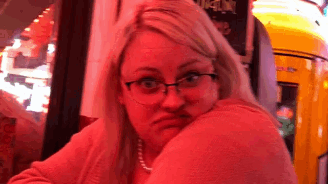 a woman wearing glasses is making a funny face in front of a sign that says ' guinness '