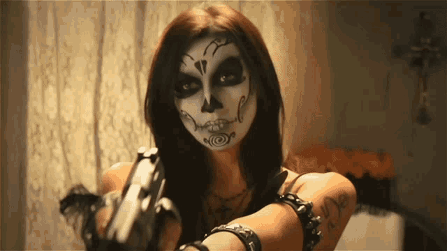 a woman with a day of the dead makeup on her face holds a gun