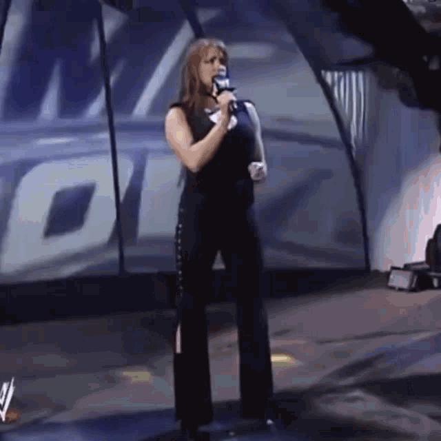 a woman is standing on a stage holding a microphone and singing into it .