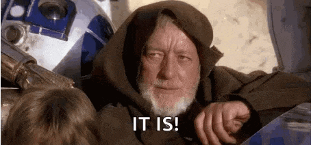 a man with a beard is sitting in front of a r2d2 robot and says `` it is ! ''