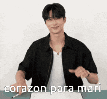 a man in a black jacket is pointing at a piece of paper with the words corazon para mari written on it
