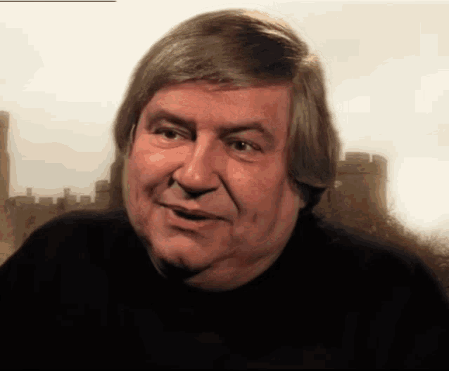 a man with long hair is smiling in front of a castle