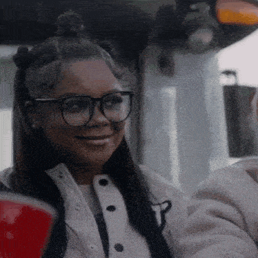 a woman wearing glasses and a white jacket smiles for the camera