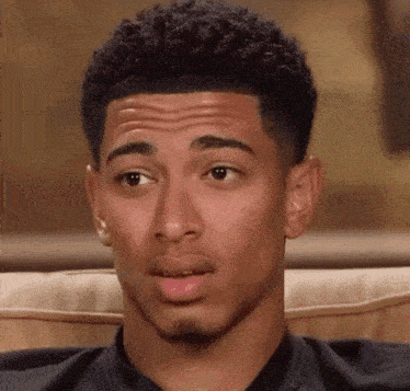 a young man sitting on a couch making a face