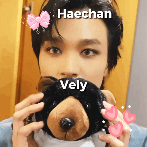 a picture of haechan holding a teddy bear with the name vely on it