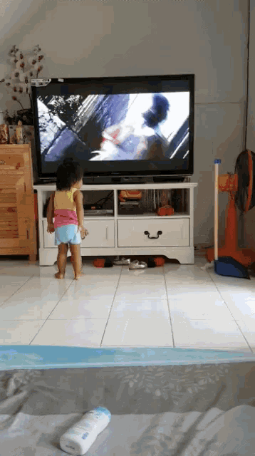a little girl is standing in front of a tv
