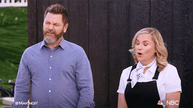 a man and a woman are standing next to each other and the woman is wearing overalls