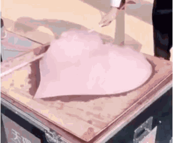 a person is cutting a heart shaped piece of ice on a wooden table .