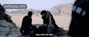 two men are sitting on a rock and one of them says stay with the ship