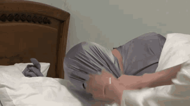 a person laying on a bed with a blanket over their face