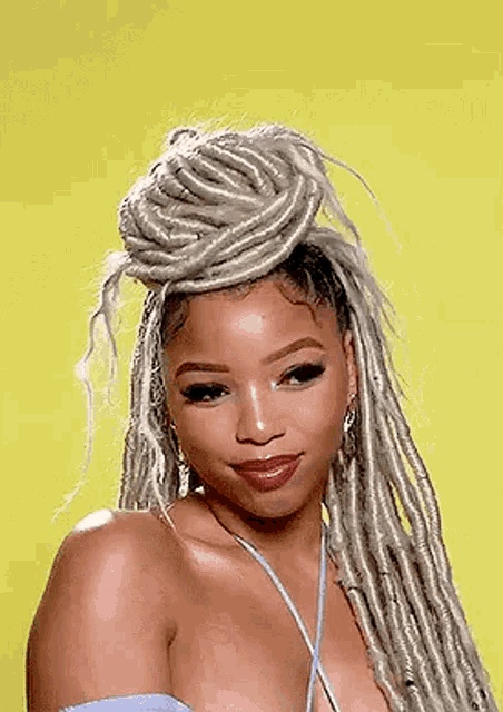 a woman with dreadlocks is wearing a blue top and a blue necklace .