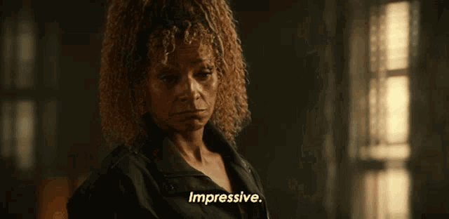 a woman with curly hair is saying impressive in a dark room