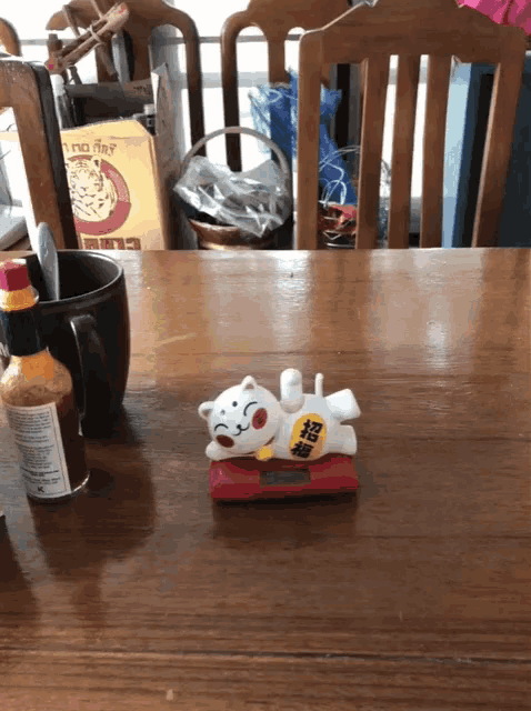 a bottle of tabasco sits on a wooden table next to a cat figurine