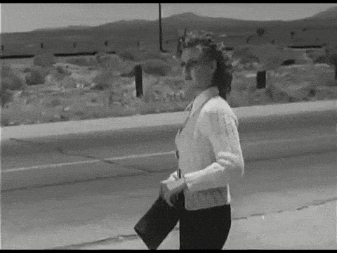 a woman in a white sweater is walking down a street