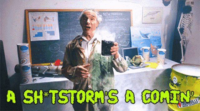 a man holding a cup in front of a chalkboard that says a sh * tstorm 's a comin '