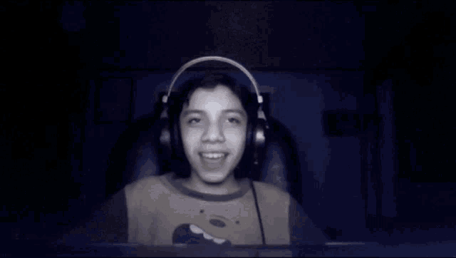 a young boy wearing headphones is waving his hands in the dark .