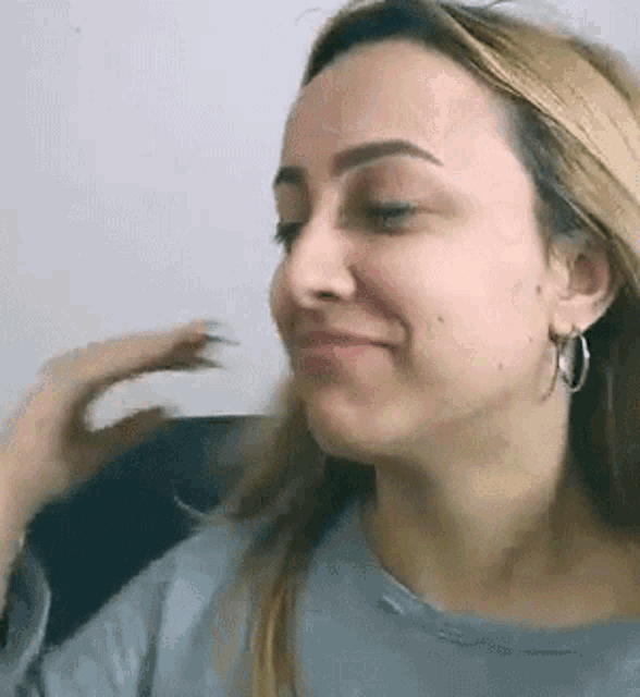 a close up of a woman 's face wearing earrings and a grey shirt .