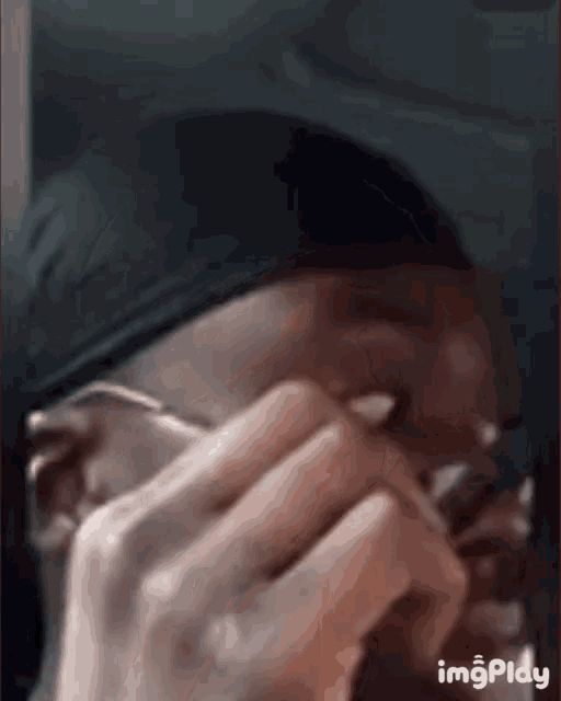 a man wearing glasses and a headband is covering his face with his hand .