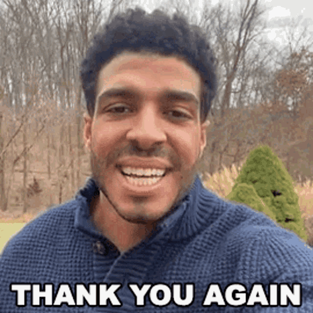 a man in a blue sweater is smiling and saying `` thank you again '' while taking a selfie .