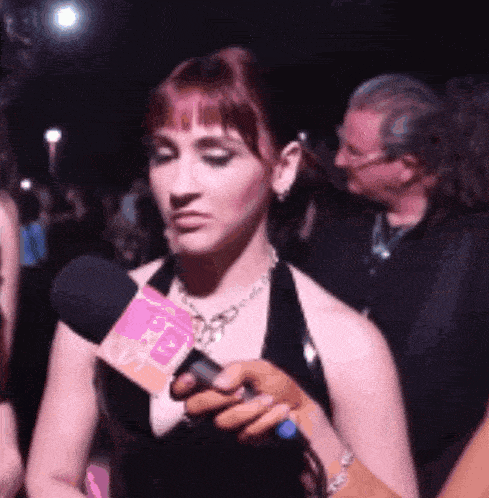 a woman is being interviewed by a person holding a microphone with a pink square that says cbs on it