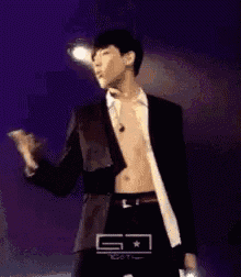 a man in a suit is dancing on a stage without a shirt .