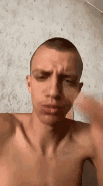 a shirtless man with a shaved head is making a face