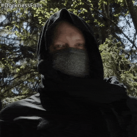 a man wearing a black hooded jacket and a mask with #dorknessfalls written below him