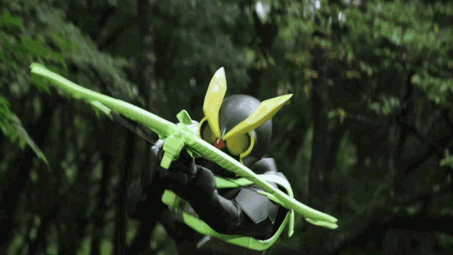 a person is holding a green sword in their hand in the woods .