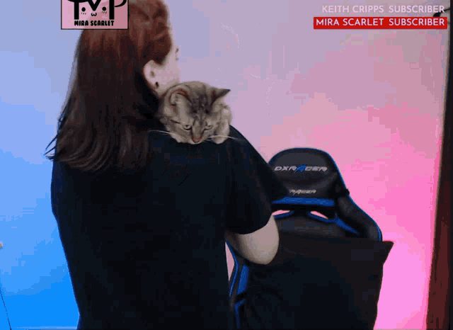 a woman is holding a cat on her shoulder in front of a chair that says dxracer on it