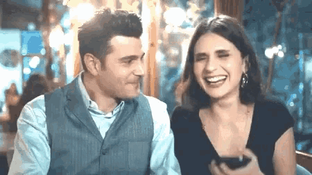 a man and a woman are laughing together at a restaurant .