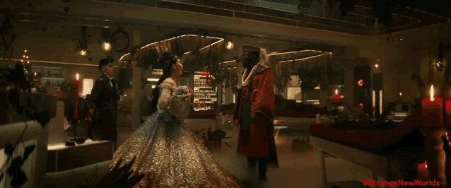 a woman in a ball gown is standing next to a man in a red costume with the hashtag #strangenewworlds