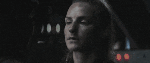 a close up of a woman 's face in a dark room with a car in the background .