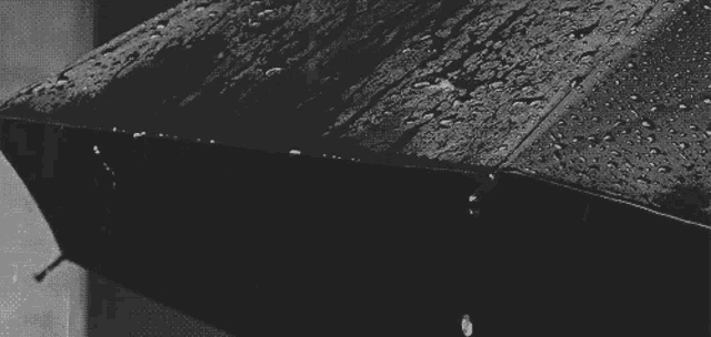 a black and white photo of rain falling on an umbrella